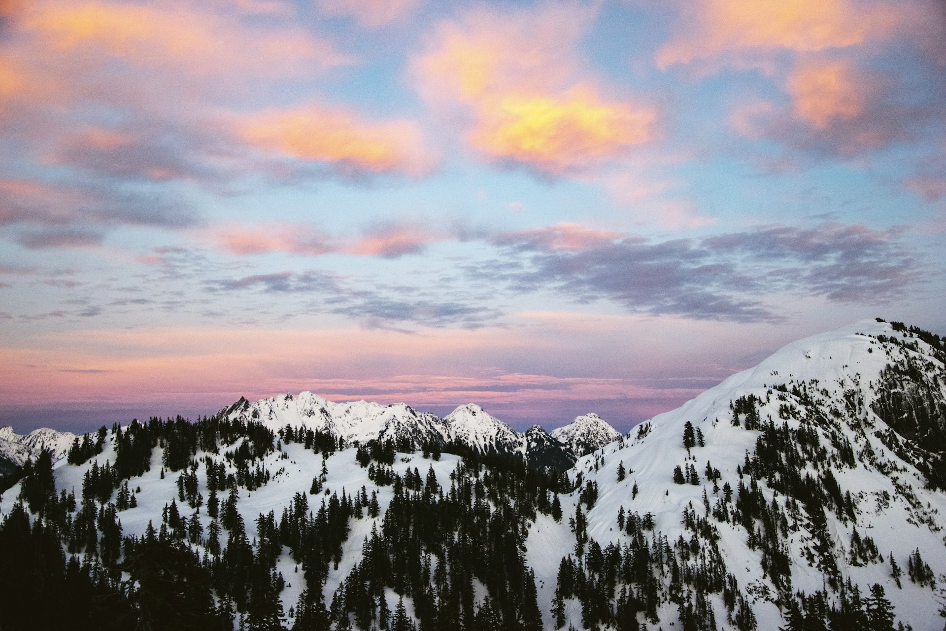North Cascades peaks at golden hour with pink and gold clouds over snow-covered mountains